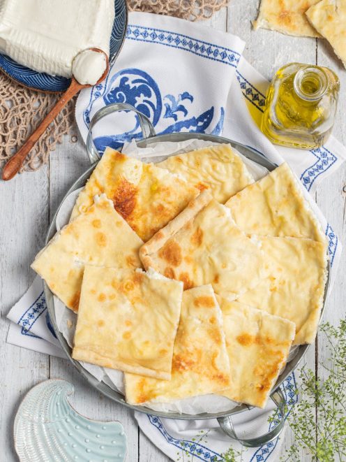 Focaccia di Recco tagliata a pezzi irregolari con ripieno di formaggio cremoso e superficie dorata