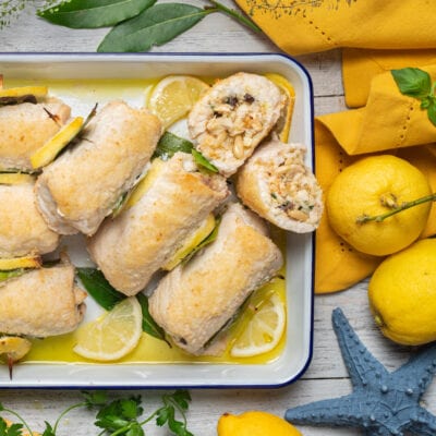 Involtini di spada alla messinese con ripieno di pinoli e uvetta, serviti con fette di limone e foglie di alloro