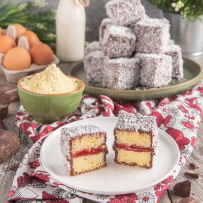 Lamingtons tagliati a metà con strato di confettura, glassa al cioccolato e cocco grattugiato