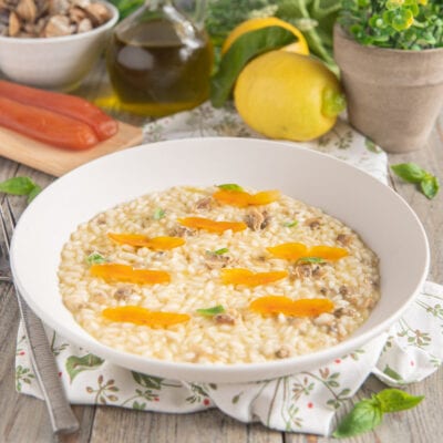 Risotto all'olio con vongole, bottarga e limone guarnito con lamelle di bottarga e foglie di basilico