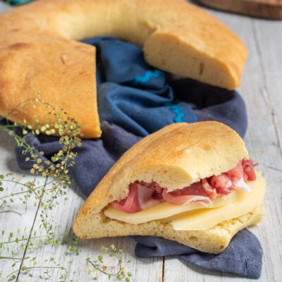 Strazzata farcita con fette di formaggio e prosciutto crudo, accanto al pane intero