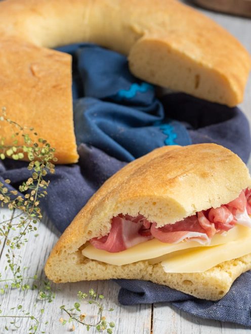 Strazzata farcita con fette di formaggio e prosciutto crudo, accanto al pane intero
