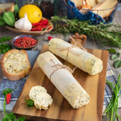 Burro aromatizzato alle erbe avvolto in carta e legato con spago, con fette tagliate in primo piano