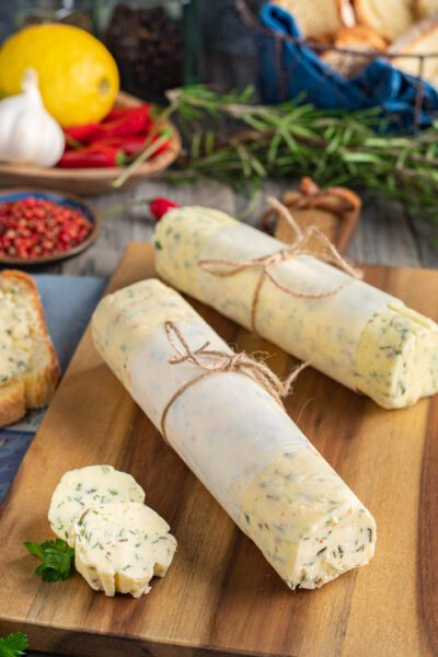 Burro aromatizzato alle erbe avvolto in carta e legato con spago, con fette tagliate in primo piano