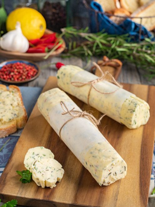 Burro aromatizzato alle erbe avvolto in carta e legato con spago, con fette tagliate in primo piano