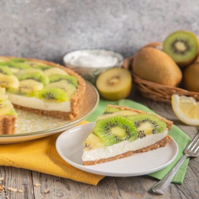 Crostata senza cottura al kiwi e yogurt con una fetta servita in primo piano