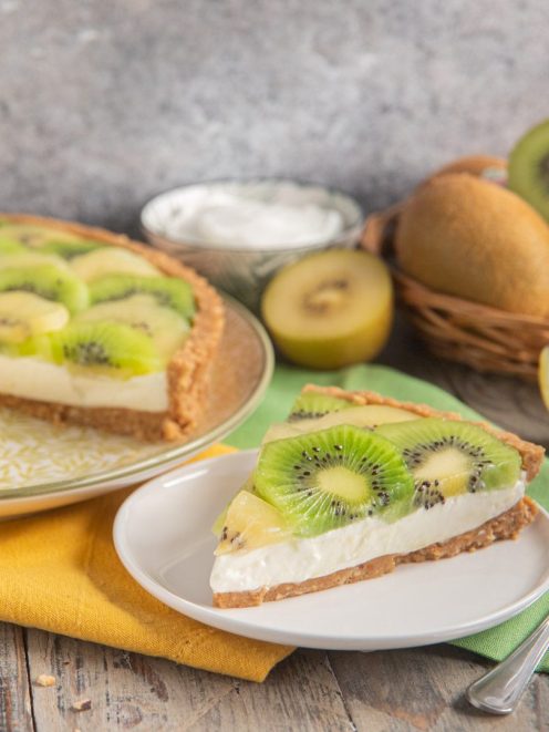 Crostata senza cottura al kiwi e yogurt con una fetta servita in primo piano