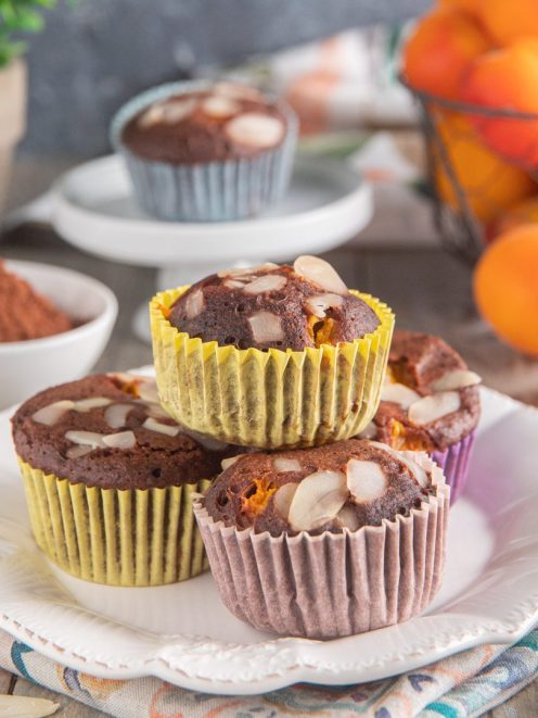 Muffin al cacao con albicocche e mandorle a scaglie, impilati su un piatto