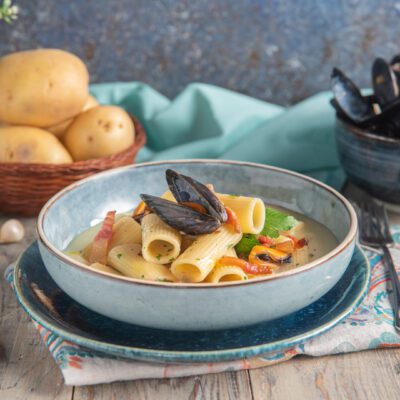 Rigatoni con crema di patate, cozze e guanciale croccante in una fondina fumante