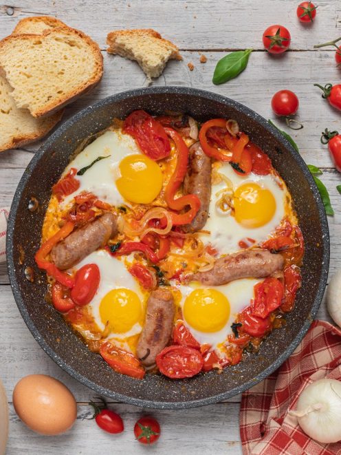 U' funnateglie con uova al tegame, salsicce, pomodori e peperoni in padella