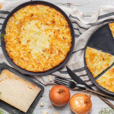 Frico dorato e croccante in padella, con una fetta già tagliata a spicchio