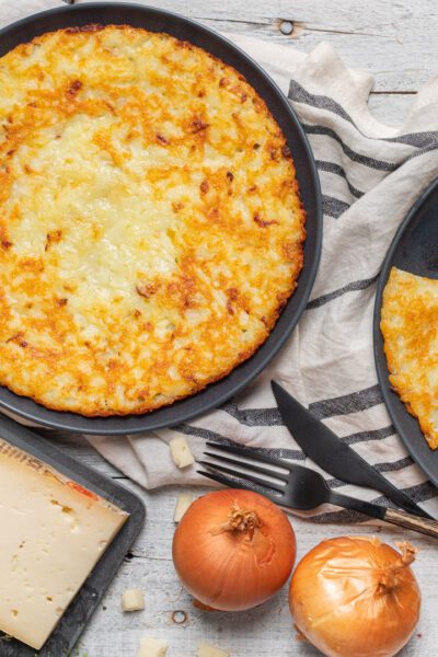Frico dorato e croccante in padella, con una fetta già tagliata a spicchio
