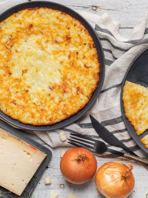 Frico dorato e croccante in padella, con una fetta già tagliata a spicchio