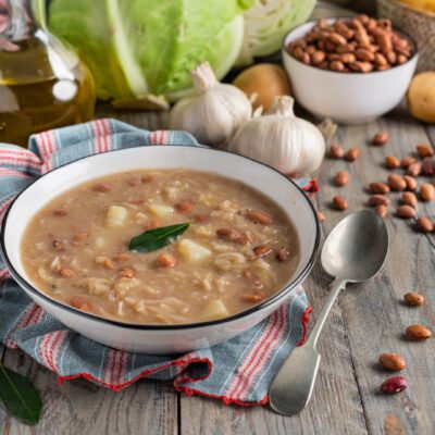 Jota densa con fagioli borlotti, pezzi di patata e una foglia di alloro