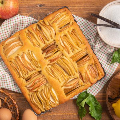 Torta soffice di mele appena sfornata con fette di mela disposte in file ordinate sulla superficie dorata