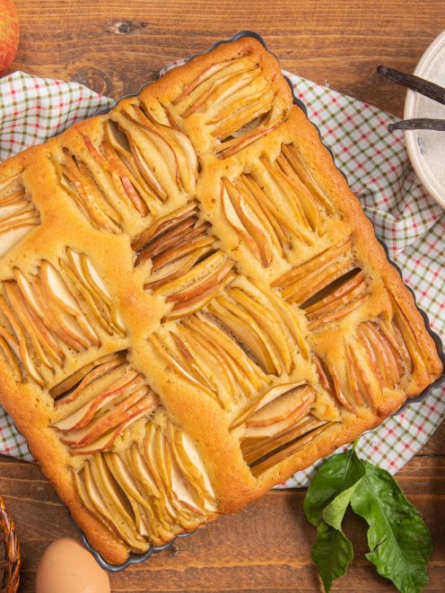 Torta soffice di mele appena sfornata con fette di mela disposte in file ordinate sulla superficie dorata