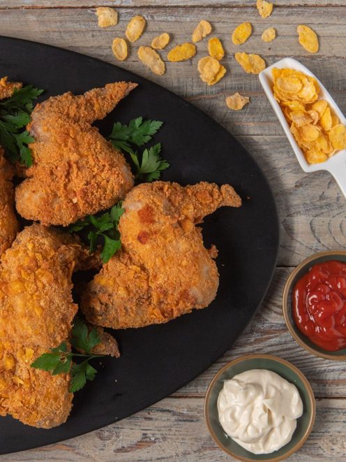 Alette di pollo speziate con panatura croccante ai corn flakes, guarnite con prezzemolo fresco