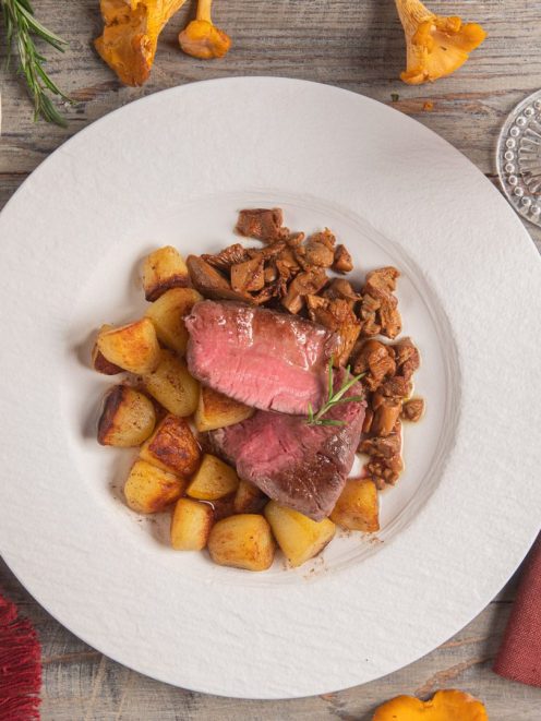 Filetto con riduzione al porto affettato al rosa, servito con patate arrosto e finferli saltati