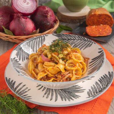 Orecchiette con ragù bianco, nduja e cipolla caramellata, guarnite con croccante di pane e ciuffi di finocchietto