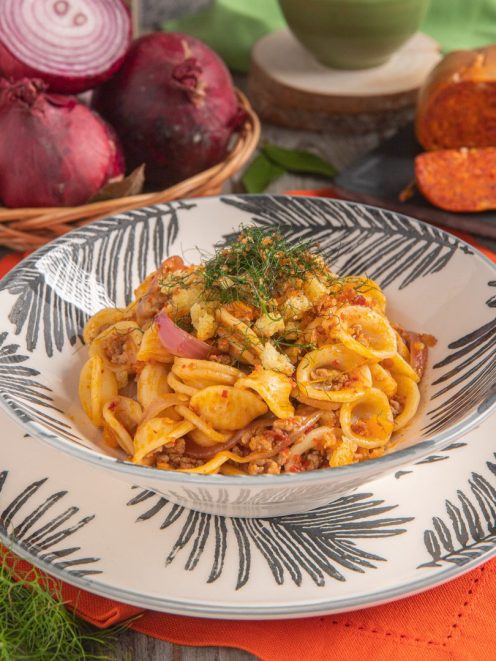Orecchiette con ragù bianco, nduja e cipolla caramellata, guarnite con croccante di pane e ciuffi di finocchietto