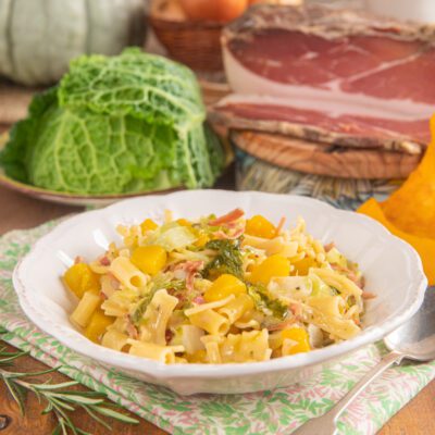 Pasta alla zucca con verza e speck, condita con dadini di zucca gialla e foglie di cavolo stufate