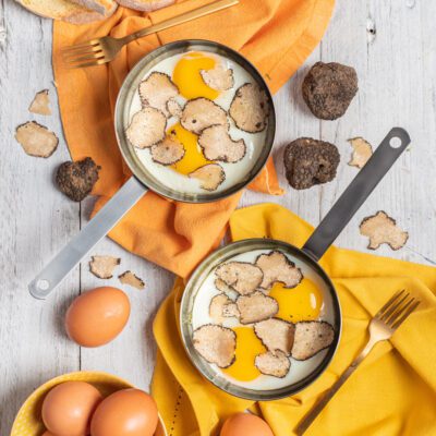 Uova al tartufo servite in padella con abbondanti lamelle di tartufo nero sul tuorlo