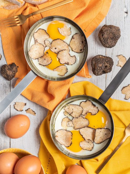 Uova al tartufo servite in padella con abbondanti lamelle di tartufo nero sul tuorlo