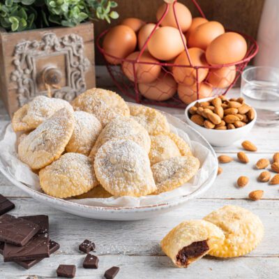 Caggionetti spolverati di zucchero a velo con ripieno al cioccolato e mandorle in vista