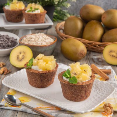 Cestini di granola con kiwi giallo e ricotta, guarniti con foglioline di menta fresca