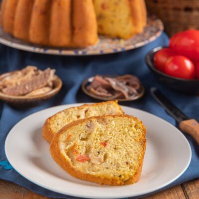 Ciambella salata affettata con tonno, pomodoro e scamorza visibili nell'impasto dorato