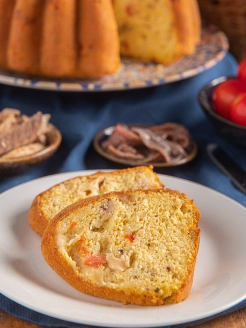 Ciambella salata affettata con tonno, pomodoro e scamorza visibili nell'impasto dorato