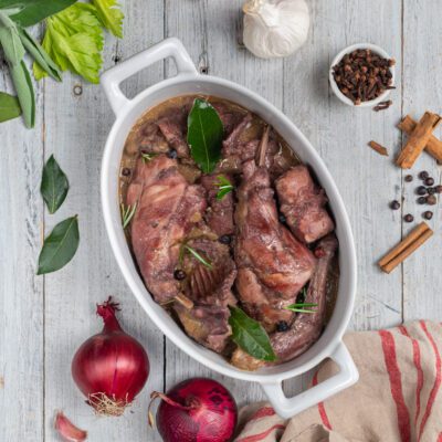 Coniglio al civet con pezzi di carne in salsa scura, alloro, rosmarino e grani di pepe