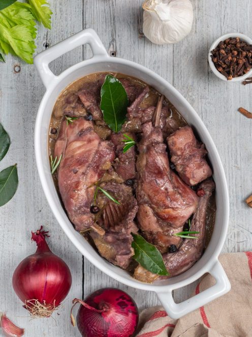 Coniglio al civet con pezzi di carne in salsa scura, alloro, rosmarino e grani di pepe