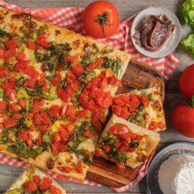 Focaccia messinese tagliata a fette con scarola, pomodori a pezzi e mozzarella filante