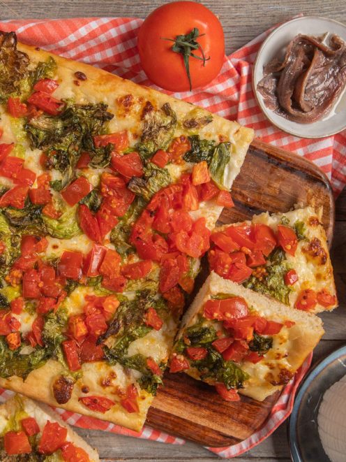 Focaccia messinese tagliata a fette con scarola, pomodori a pezzi e mozzarella filante