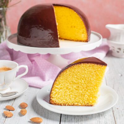 Parrozzo a cupola ricoperto di glassa al cioccolato con una fetta tagliata che rivela l'interno giallo