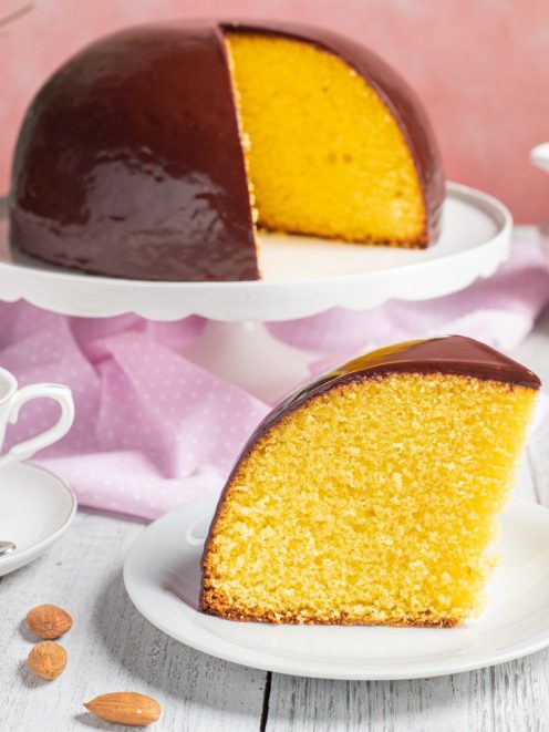 Parrozzo a cupola ricoperto di glassa al cioccolato con una fetta tagliata che rivela l'interno giallo