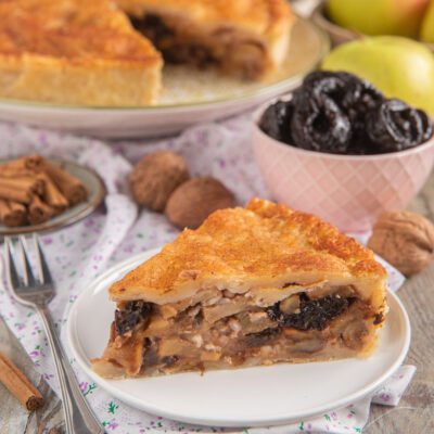 Fetta di pie di mele con prugne secche e noci, pasta dorata spolverata di cannella