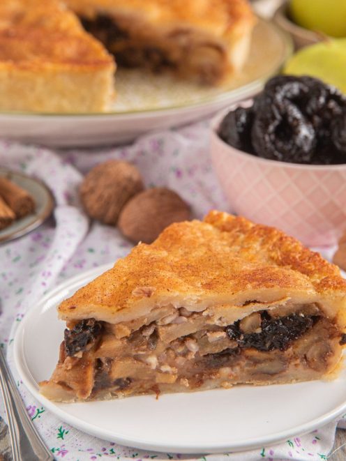 Fetta di pie di mele con prugne secche e noci, pasta dorata spolverata di cannella