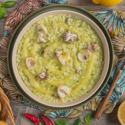 Risotto con crema di patate e seppioline mantecato al pesto, con vortice di salsa gialla