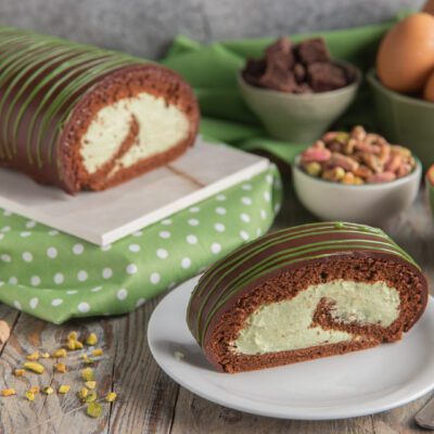 Rotolo al pistacchio con pan di spagna al cacao, crema verde e glassa striata servito a fette