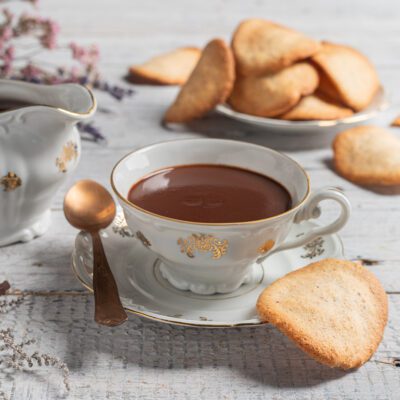 Tegole valdostane servite accanto a una tazza di crema di Cogne densa e lucida