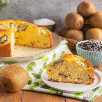 Torta 7 vasetti ai kiwi con fetta tagliata che mostra l'impasto soffice con gocce di cioccolato e kiwi caramellati in superficie
