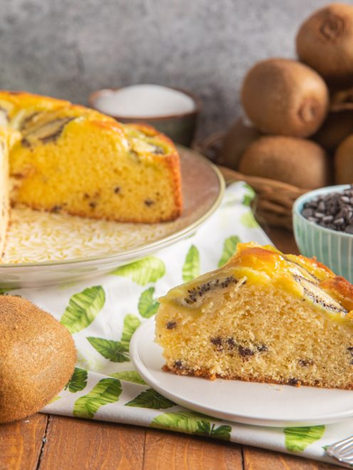 Torta 7 vasetti ai kiwi con fetta tagliata che mostra l'impasto soffice con gocce di cioccolato e kiwi caramellati in superficie