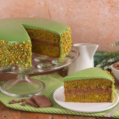 Torta al pistacchio e cioccolato a strati con glassa verde, granella di pistacchi e farcitura al cioccolato