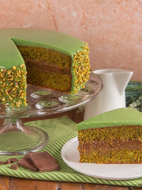 Torta al pistacchio e cioccolato a strati con glassa verde, granella di pistacchi e farcitura al cioccolato