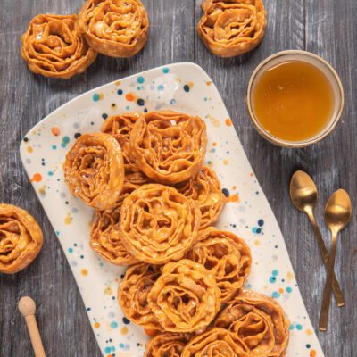 Cartellate fritte a forma di rosa glassate con miele ambrato, servite su vassoio