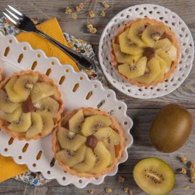 Crostatine alla crema e kiwi giallo disposte a ventaglio su pasta frolla dorata