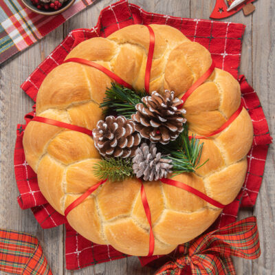 Ghirlanda di Natale in pan brioche dorato decorata con pigne e rametti di pino
