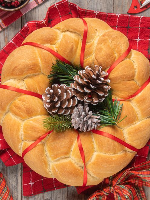 Ghirlanda di Natale in pan brioche dorato decorata con pigne e rametti di pino